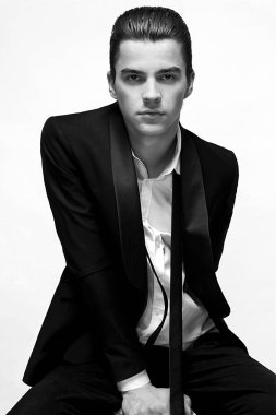 Beyaz arka plan üzerinde oturan takım elbiseli yakışıklı genç