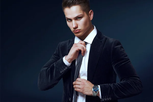 Elegante uomo in abito nero e cravatta su sfondo blu — Foto Stock