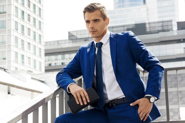 Güneşli bir günde bir şehir arka plan mavi elbiseli yakışıklı adam