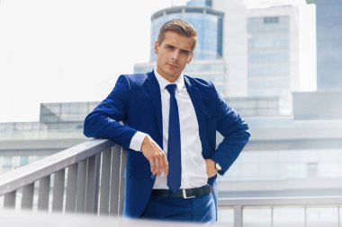 Güneşli bir günde bir şehir arka plan mavi elbiseli yakışıklı adam