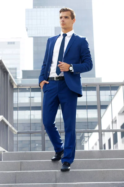 Hombre guapo en un traje azul contra un fondo de la ciudad en un día soleado —  Fotos de Stock