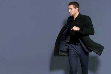 bir gri arka plan stüdyo üzerinde siyah paltolu adam