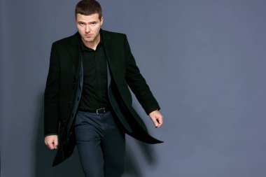 bir gri arka plan stüdyo üzerinde siyah paltolu adam