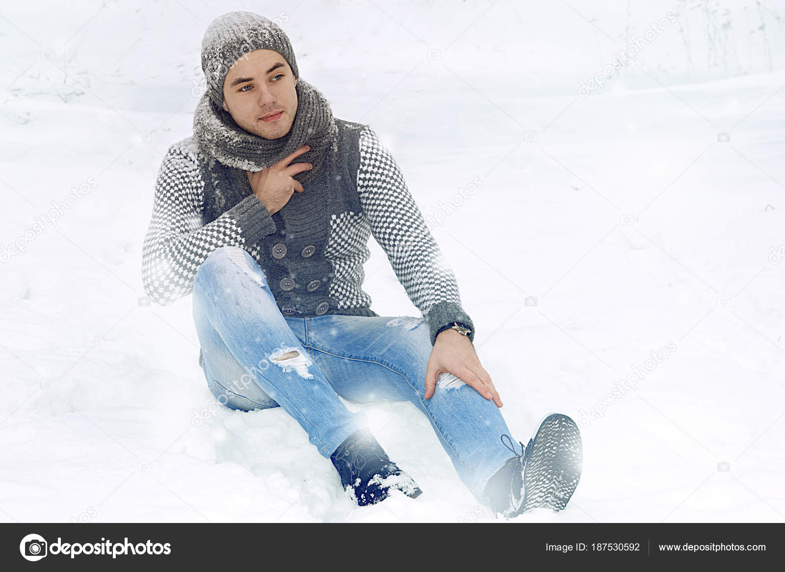 ニットのセーターの男と雪の中に座っている帽子 ストック写真 C Andre13