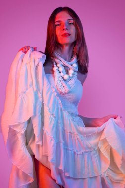 Genç ve zarif bir kızın moda portresi. Renkli neon arka plan, stüdyo çekimi. Güzel esmer kadın..