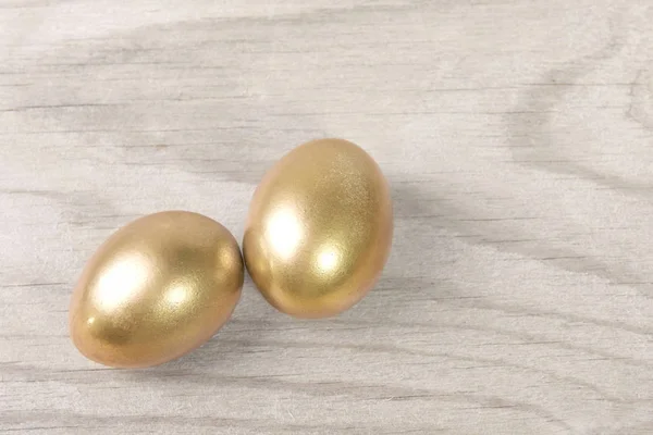 Oeufs dorés de Pâques sur fond de table en bois blanc — Photo