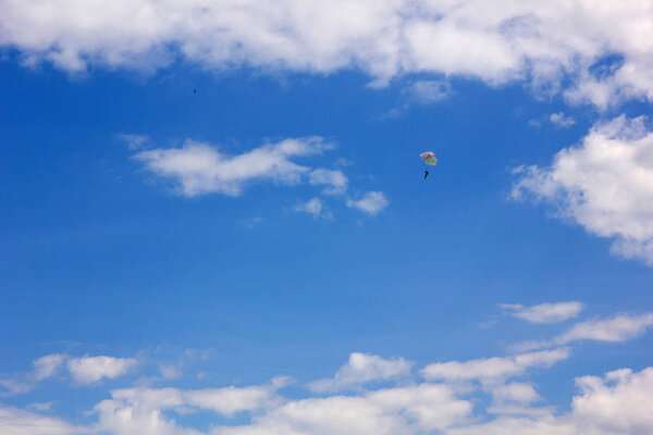 Parachutist on the background of blue sky with white clouds