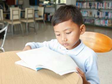 Asyalı çocuk Kütüphanesi'nde kitap okuma.