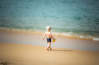 Genç çocuk içinde belgili tanımlık kum plaj vintage tarzı üzerinde oynama.