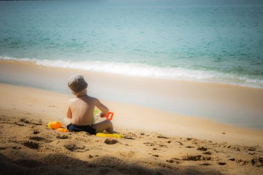 Genç çocuk içinde belgili tanımlık kum plaj vintage tarzı üzerinde oynama.