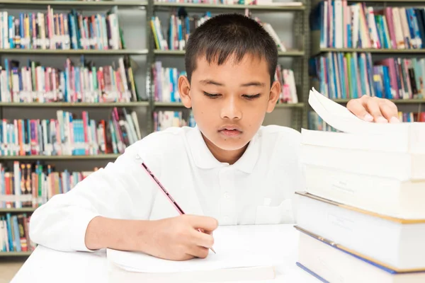 亚洲男孩做作业在图书馆 — 图库照片