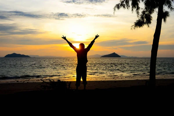 silhouette boy praying to god on the beach at sunset.