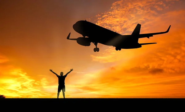 Silhouette Eines Mannes Der Bei Sonnenuntergang Mit Einem Flugzeug Für Stockfoto