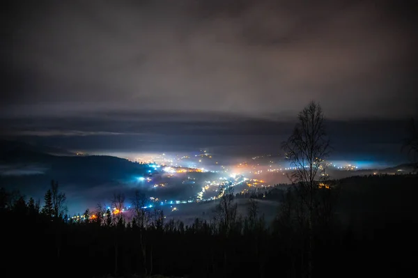 Night city in the fog in the mountains in autumn