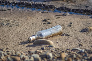 Çöpe atılmış bir cam şişe yerde yatıyor.