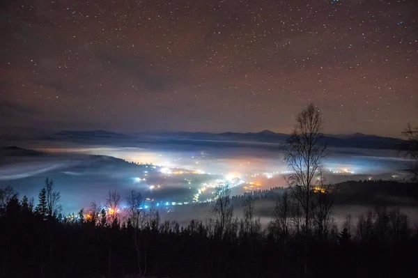 Ciudad nocturna en la niebla en las montañas en otoño — Foto de Stock