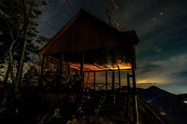 Geceleri dağın tepesindeki ahşap bina.
