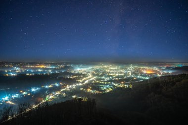 Gece şehrinin üzerinde yıldızlı gökyüzü