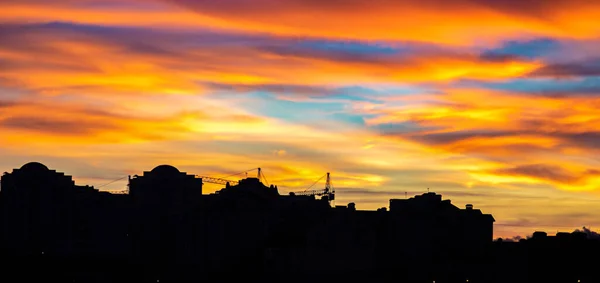 Panorama de cielo colorido atardecer sobre las siluetas de las casas —  Fotos de Stock