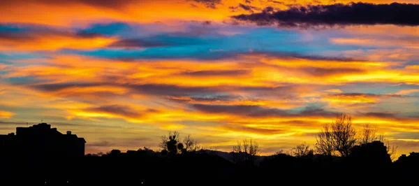 Панорама красочного закатного неба над силуэтами домов — стоковое фото