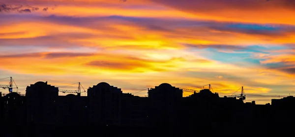 Panorama de cielo colorido atardecer sobre las siluetas de las casas —  Fotos de Stock