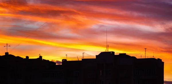 Panorama de cielo colorido atardecer sobre las siluetas de las casas —  Fotos de Stock