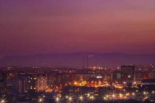 Красное небо заката над городом и силуэт гор — стоковое фото