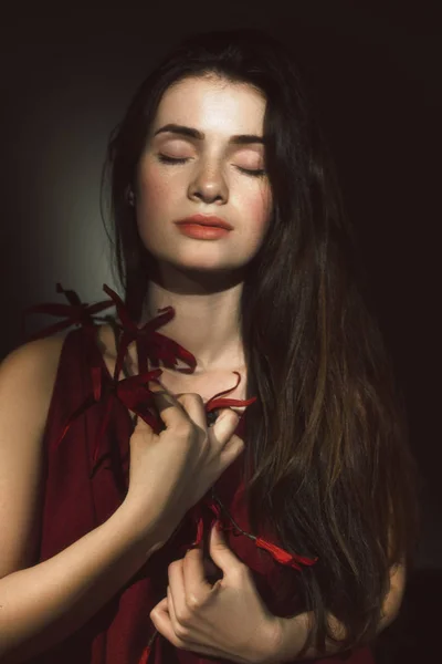 Brunette met gesloten ogen en bloemen in haar handen Stockfoto