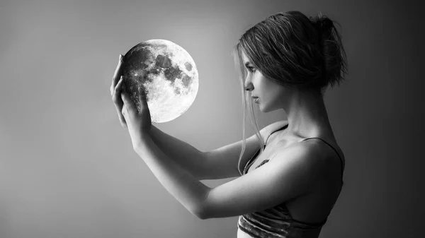 Mooi meisje houdt de maan in haar handen Stockfoto