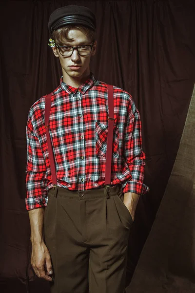 Un joven con una elegante camisa a cuadros y una gorra negra — Foto de Stock