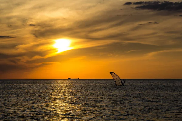Silueta de un surfista de viento en la puesta de sol olas — Foto de Stock