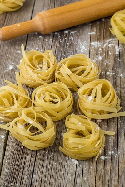 Nidi di pasta di fettuccine crude sullo sfondo del legno — Foto Stock