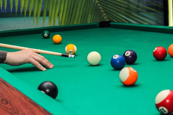 Більярдні кульки на зеленому столі і рука з києм — стокове фото