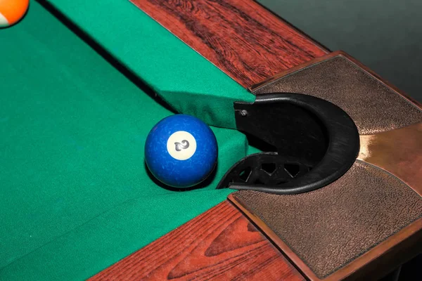 Більярдні кульки на зеленому столі і синя кулька в кишені — стокове фото
