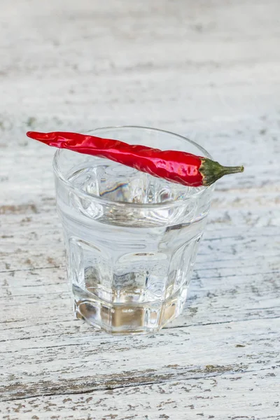 Shot of vodka with pepper on an old wooden table — Stock Photo, Image