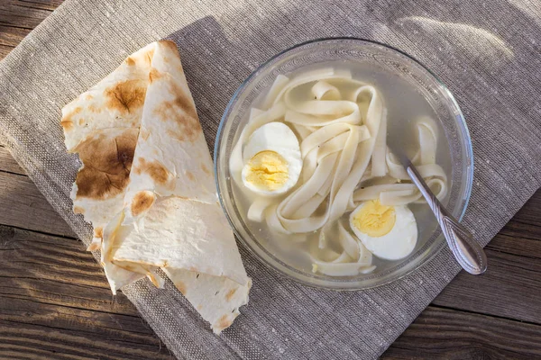 cup of chicken soup with noodles and eggs