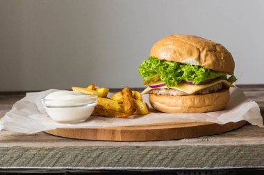 Ev yapımı hamburger tavuk, soğan, salatalık, marul ve peynir ile patates kızartması ahşap tablo
