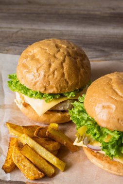 Ev yapımı hamburger tavuk, soğan, salatalık, marul ve peynir ile patates kızartması ahşap tablo