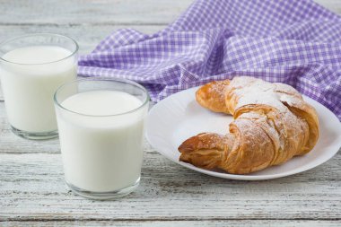 Kruvasan kahvaltı arka plan için eski ahşap masa üzerinde süt ile.