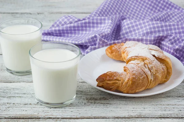 Kruvasan kahvaltı arka plan için eski ahşap masa üzerinde süt ile.