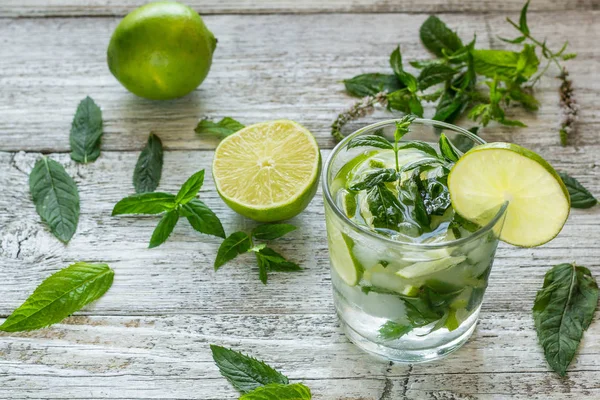 Cóctel Mojito con lima y menta en vaso de tubo sobre fondo de madera blanca — Foto de Stock