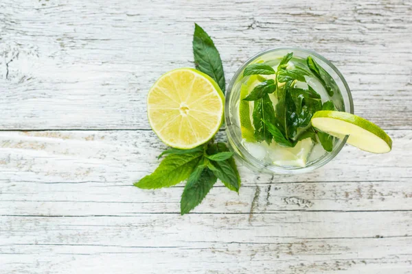 Cóctel Mojito con lima y menta en vaso de tubo sobre fondo de madera blanca Vista superior — Foto de Stock