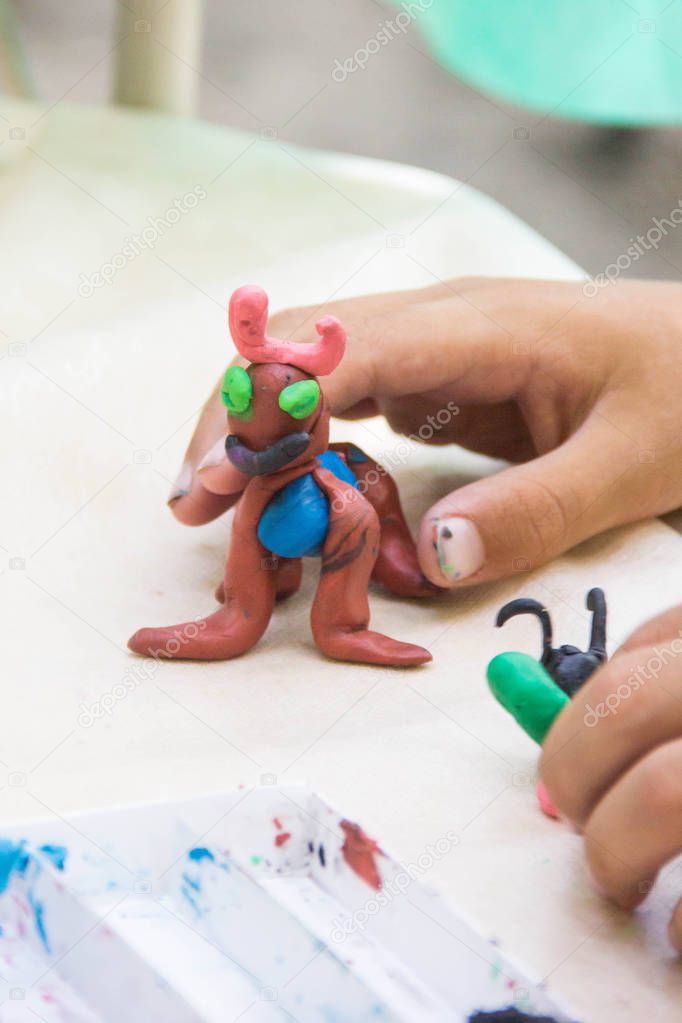 Child playing with colorful clay making animal figures. closeup on hands