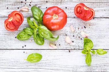 kara biber, sarımsak, fesleğen ve domates. Yemek pişirmek için malzemeler. Beyaz ahşap zemin üzerine