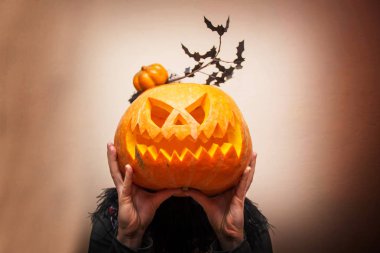 kız siyah bir zemin üzerine bir kabak kafa yerine düzenlenen bir yüz ile tutuyor. Kutlama kavramı Cadılar Bayramı