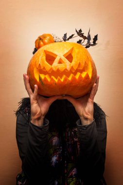 kız siyah bir zemin üzerine bir kabak kafa yerine düzenlenen bir yüz ile tutuyor. Kutlama kavramı Cadılar Bayramı