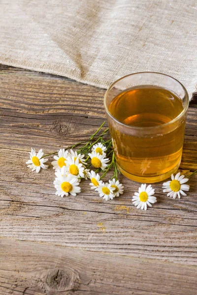 Чашка чая с ромашкой цветов на деревенском деревянном фоне — стоковое фото