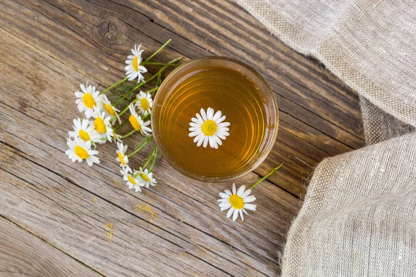 Чашка чая с ромашкой цветов на деревенском деревянном фоне — стоковое фото