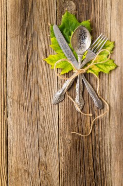 Rustik ahşap kurullarında sonbahar akşam yemeği yer ayarı için Şükran Günü tatili ile renkli akçaağaç yaprakları