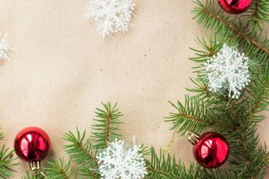 Çam dalları üzerinde kırmızı topları ve rustik bej renkli arka plan üzerinde kar taneleri ile şenlikli Noel sınır